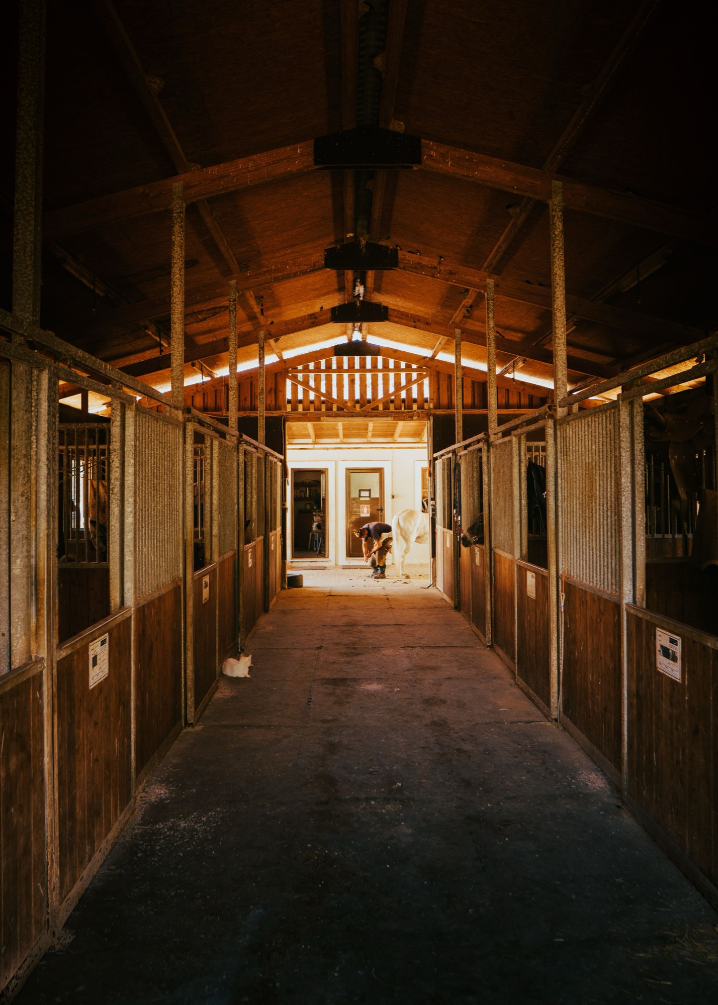 The lit central aisle of a timber stable block