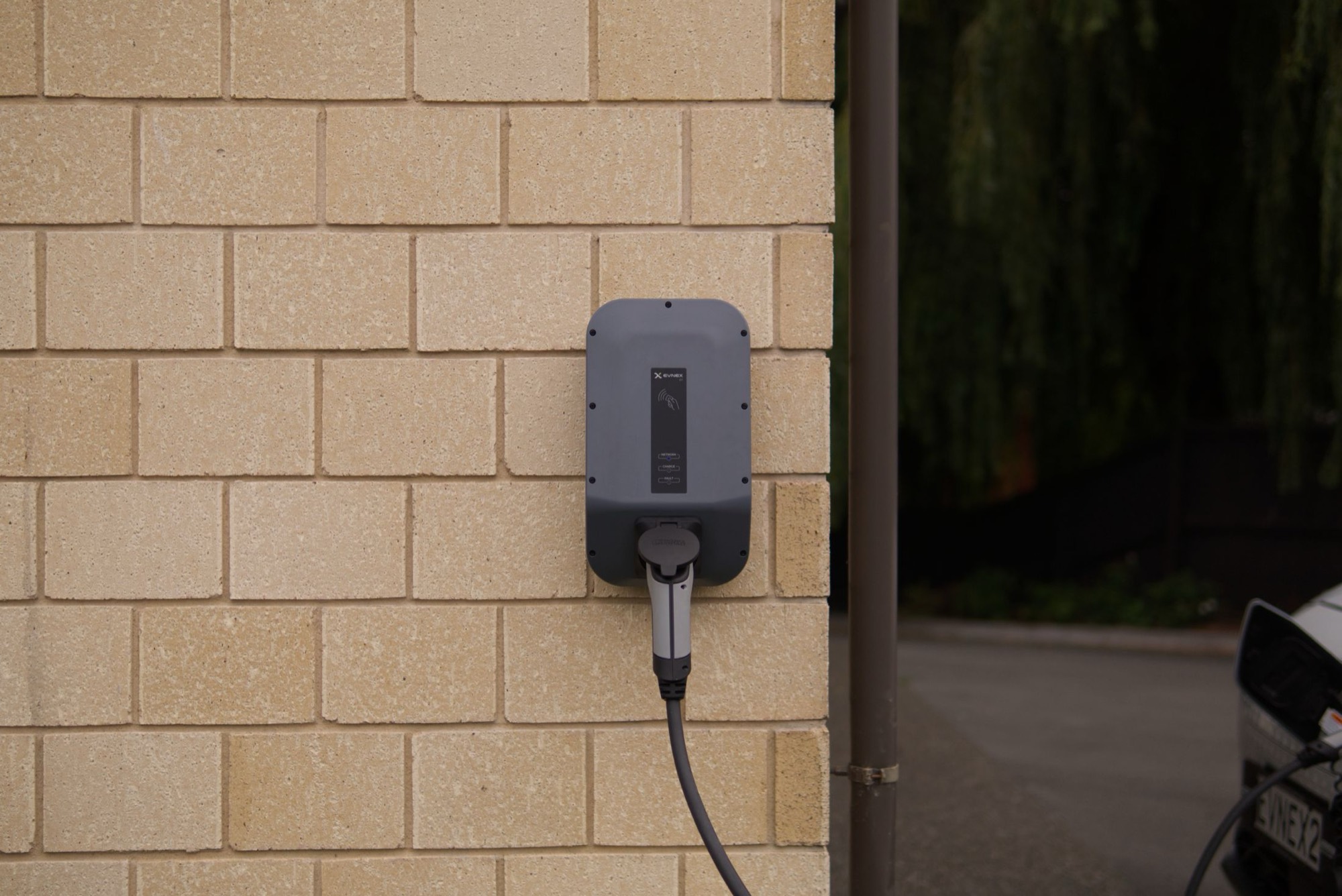 A wall-mounted EV charger fitted to the side of a house